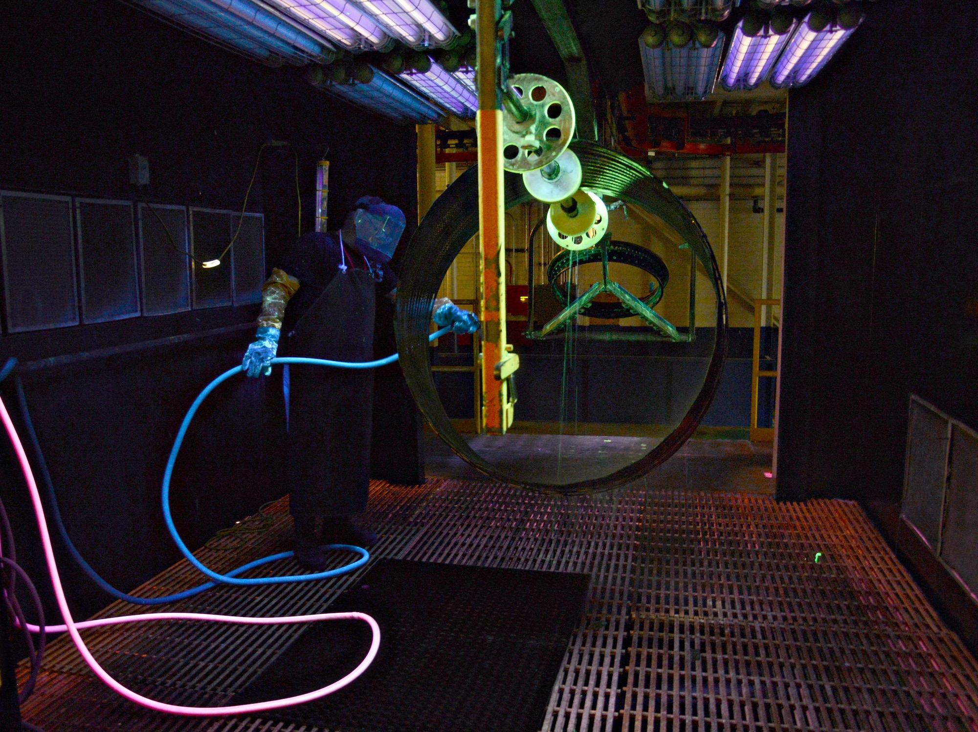 Tracy McGehee, a fluorescent penetrant inspector with the 548th Propulsion Maintenance Squadron, rinses a florescent penetrant wash off of a liner duct for a combustion chamber off of an F101 engine in a bay in his shop area. After the part has been thoroughly rinsed and dried, it will be sent to the blacklight room, where inspectors will be able to quickly detect any compromises or cracks under a black light. (Air Force photo by Kelly White/Released)