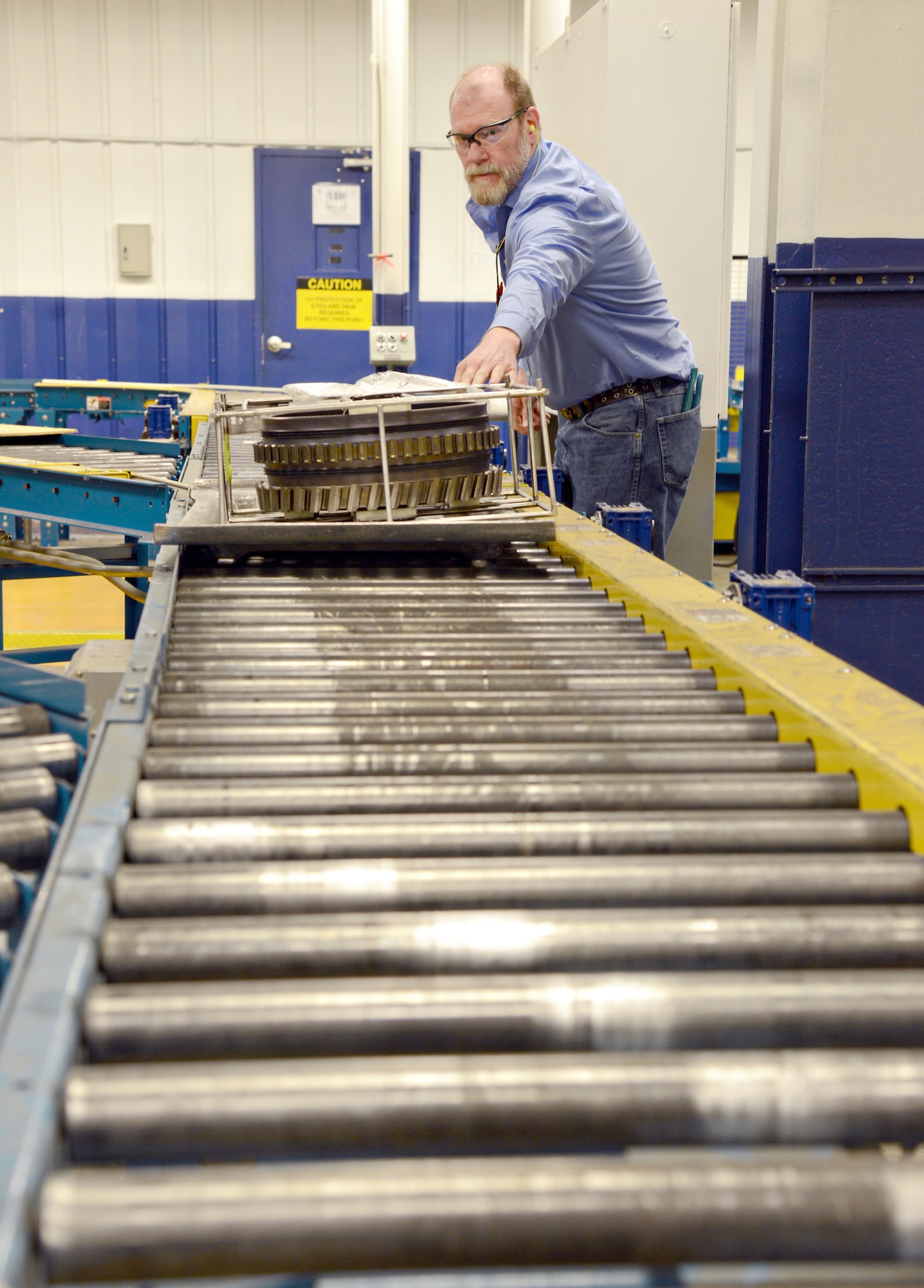 Jason Morrison, the fluorescent penetrant inspection work leader from the 548th Propulsion Maintenance Squadron, places an engine part on a conveyor belt that will be sorted and sent to the correct shop within the Non-Destructive Inspection area. Tinker’s NDI shop can perform all five methods of inspection: fluorescent penetrant inspection, magnetic particle inspection, eddy current inspection, ultrasonic inspection and X-ray/radiographic inspection. (Air Force photo by Kelly White/Released)