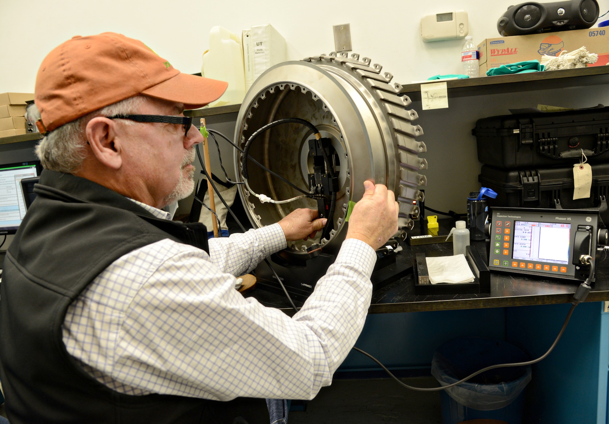 Steve Guinn, the work leader for Eddy Current and Ultrasonic inspections, performs a Phasor Ray inspection on a second stage fan disk for the F110 engine. Ultrasonic sound waves from the ray helps amplify the sound of a compromise, or a crack, in the part. (Air Force photo by Kelly White/Released)