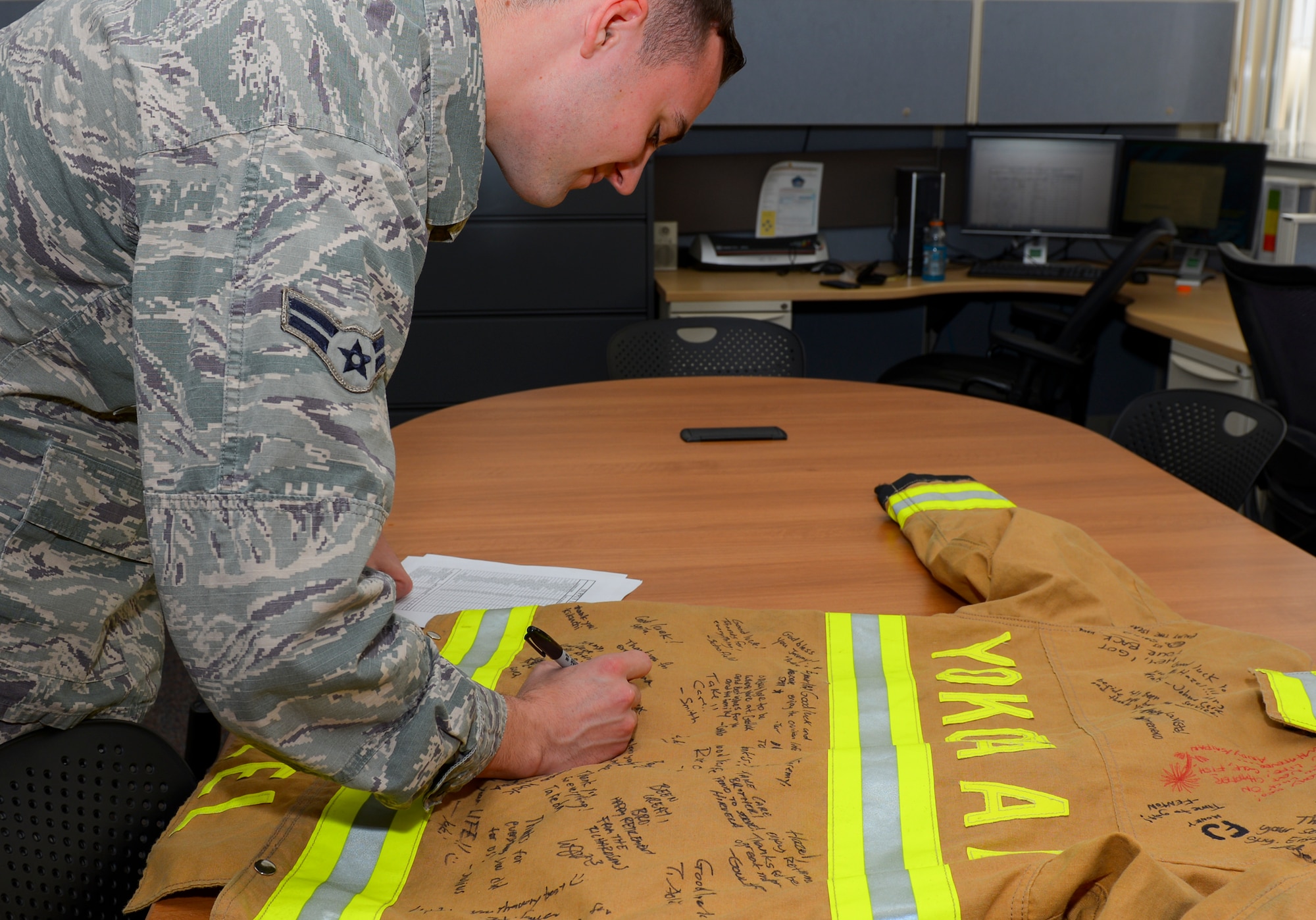 Airman 1st Class Brendan Ryan, 374th Civil Engineer Squadron fire and emergency services flight firefighter, signs a fire protection jacket at Yokota Air Base, Japan, March 28, 2016. Members of the fire and emergency services flight signed the jacket in recognition of a retiring member. (U.S. Air Force photo by Airman 1st Class Elizabeth Baker/Released) 