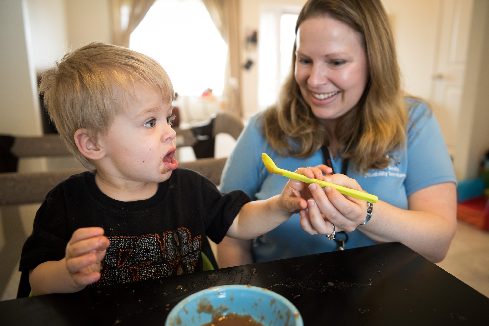 Maj. Amy Hansen, 940th Wing Inspector General and occupational therapist in the private sector teaches one of her clients how to use a spoon at his home on March 25, 2016 at Beale Air Force Base, California. As an occupational therapist, Hansen helps people with various disabilities live a more fulfilling life by teaching them how to do things that will help them be more self-sufficient. (U.S. Air Force Photo/ Staff Sgt. Brenda Davis)