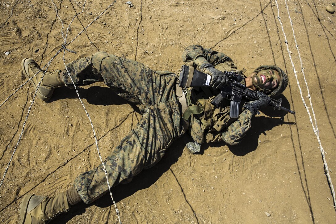 Marine Corps Private Michael L. Riddle craws under concertina wire during an event at Marine Corps Base Camp Pendleton, Calif., March 23, 2016. Riddle, assigned to Delta Company, 1st Recruit Training Battalion, is graduating as a squad leader. Marine Corps photo by Sgt. Tyler Viglione