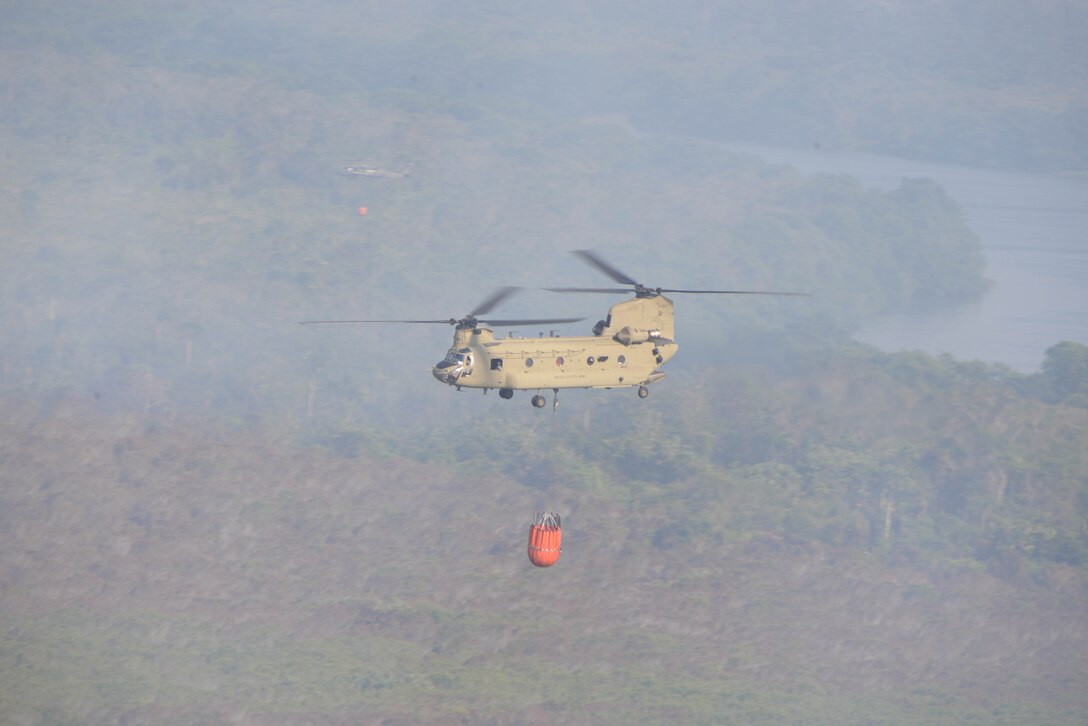 A U.S. Army CH-47 Chinook and UH-60 Black Hawk provide Bambi Bucket firefighting capabilities in support of a Honduran effort to extinguish a forest fire, March 31, 2016, near Tela Honduras, at the request of Honduran President Juan Orlando Hernandez. The two aircraft were a part of a package of helicopters that Joint Task Force-Bravo, located at Soto Cano Air Base, Honduras, sent to help the Hondurans respond to the fire. (U.S. Air Force photo by Staff Sgt. Westin Warburton/ Released)