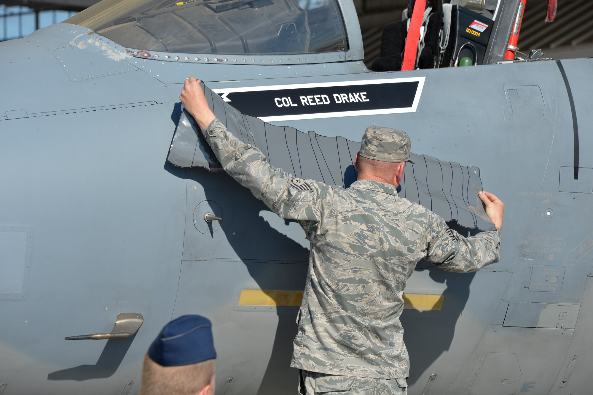 U.S. Air Force Tech. Sgt. Robert Martin, 144th Maintenance Squadron crew chief,  unveils Col. Reed Drake's, the incoming commander, name on the wing's flagship F-15 during the change of command ceremony here April 2, 2016. (U.S. Air National Guard photo by Tech. Sgt. Charles Vaughn)