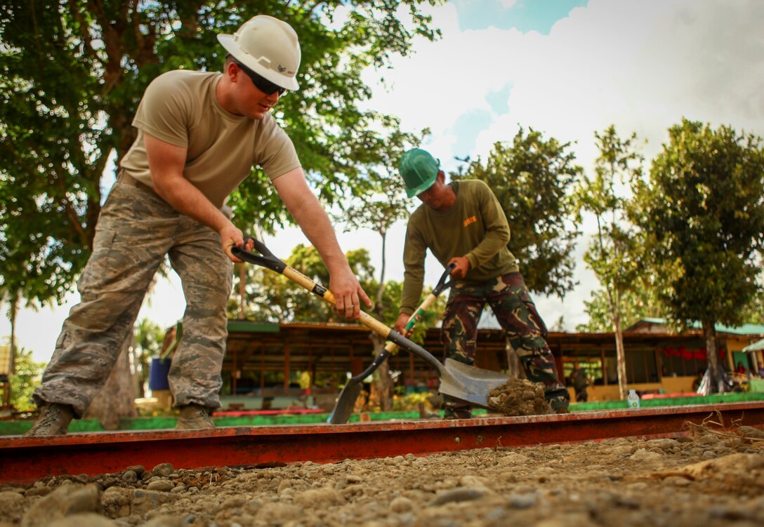 U.S. Air Force Staff Sgt. Kyle Gould, left, engineer, assigned to the 673D Expeditionary Engineer Squadron and Philippine army soldier Cpl. Gilbert Balobalo, right, engineer, assigned to 552 Engineer Construction Battalion, level dirt for a basketball court being constructed at Jaena Norte Elementary School in Capiz, Philippines, as part of a humanitarian civic assistance (HCA) project during Exercise Balikatan 2016, April 2, 2016. The construction project is one of multiple HCAs taking place during this year's exercise, designed to improve the quality of life for the local populace and strengthen the bond between our two nations. Balikatan, which means "shoulder to shoulder" in Filipino, is an annual bilateral training exercise aimed at improving the ability of Philippine and U.S. military forces to work together during planning, contingency and humanitarian assistance and disaster relief operations. 