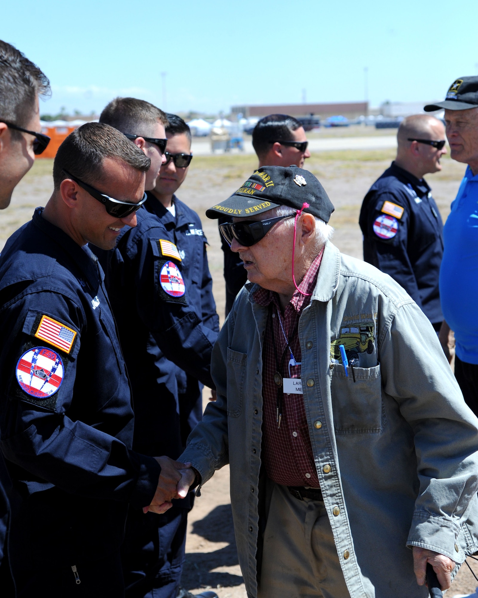 Larry Miel, WWII veteran, shakes hands with F-35 Heritage Flight Team members before the practice for the Luke Air Force Base air show Apr 1, 2016.  Several WWII veterans came out to view the practice event which included performances from the U.S. Thunderbirds and the  F-35 Heritage Flight Team.