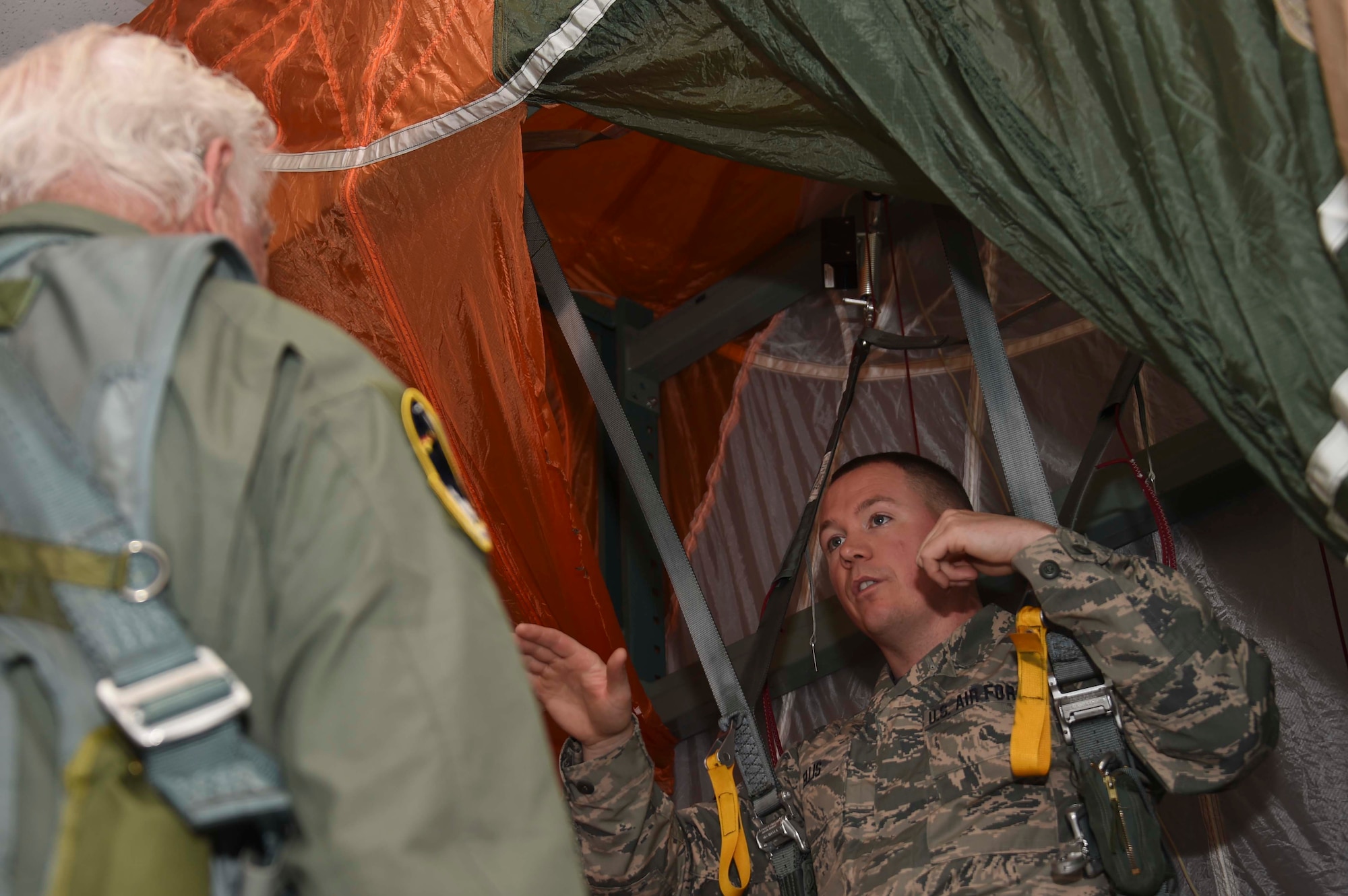 U.S. Air Force Tech. Sgt. Johnny Ellis, 144th Operations Group aicrew flight equipment technician, demonstrates proper parachute handling procedures to U.S. Air Force Brig. Gen. (ret.) Robert Earthquake Titus at the Fresno Air National Guard Base April 1, 2016. Titus is the 144th Fighter Wing's 3rd Annual Heritage Week honored guest, who shared his personal experiences as a fighter pilot with the 144th FW Airmen. (U.S. Air National Guard photo by Senior Airman Klynne Pearl Serrano)
