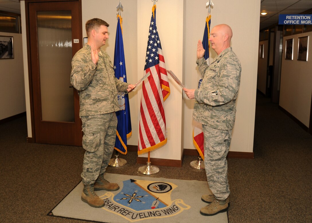 Col. Scott Plambeck, the Vice Commander of the 185th Air Refueling Wing, reads the oath of enlistment to Tech. Sgt. Eric Olson in Sioux City, Iowa, April 3, 2016. Olson was the 100th recruit of Staff Sgt. Wesley Rueter, a recruiter assigned to the 185th ARW. (U.S. Air National Guard photo by Staff Sgt. Daniel S. Ter Haar./Released)