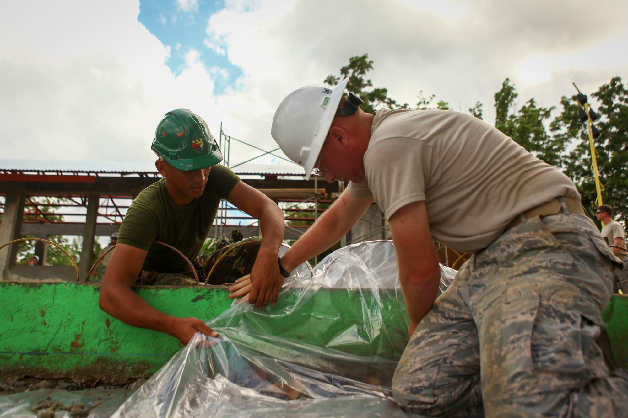 U.S. Air Force Tech. Sgt. Jeremiah Shelton, right, engineer, assigned to the 673rdD Expeditionary Engineer Squadron and Philippine army soldier Pfc. Mhar Calapano, left, engineer, assigned to 552nd Engineer Construction Battalion, lay down heavy duty plastic to cover a basketball court being constructed at Jaena Norte Elementary School in Capiz, Philippines, as part of a humanitarian civic assistance (HCA) project during Exercise Balikatan 2016, April 2, 2016. The construction project is one of multiple HCAs taking place during this year's exercise, designed to improve the quality of life for the local populace and strengthen the bond between our two nations. Balikatan, which means "shoulder to shoulder" in Filipino, is an annual bilateral training exercise aimed at improving the ability of Philippine and U.S. military forces to work together during planning, contingency and humanitarian assistance and disaster relief operations. (U.S. Marine Corps Combat Camera photo by Cpl. Hilda M. Becerra / Released)