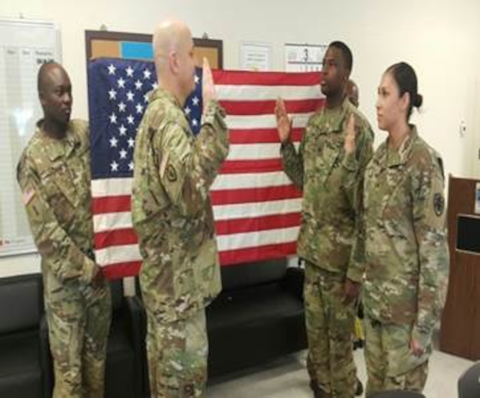 DLA Distribution Korea commander Army Lt. Col. Mark Wolf reenlists Sgt. Stephanie Swann and her husband Sgt. Jonathan Swann in a reenlistment ceremony on March 7.