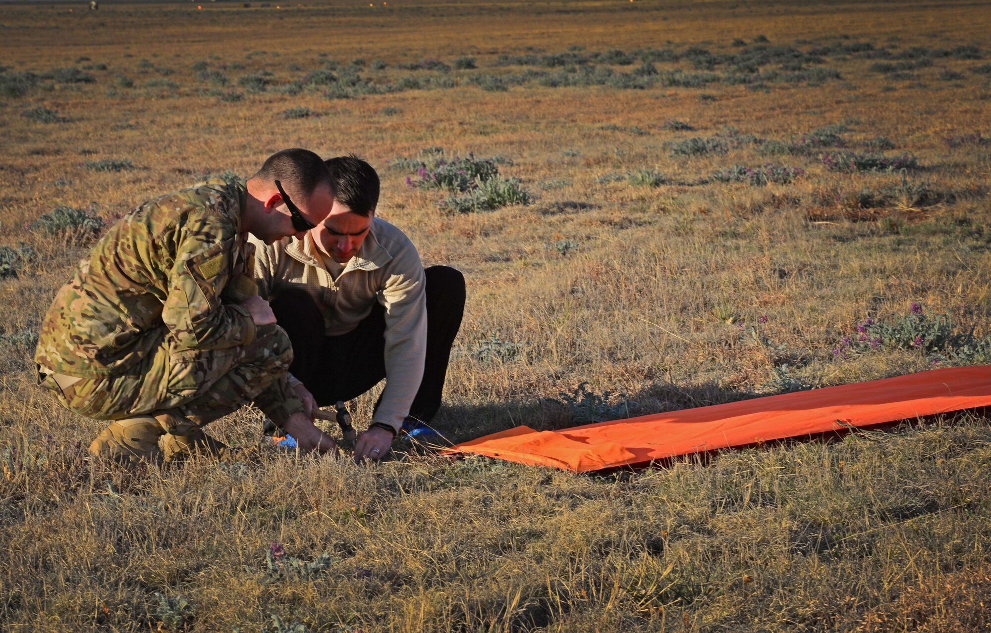 Two team members with the 26th Special Tactics Squadron prepare secure a marker for a landing zone March 25, 2016, at Cannon Air Force Base, N.M. This helped other 26th STS members performing routine practice jumps over the Cannon flightline safely identify their target landing area. (U.S. Air Force photo/Staff Sgt. Alexx Pons) 