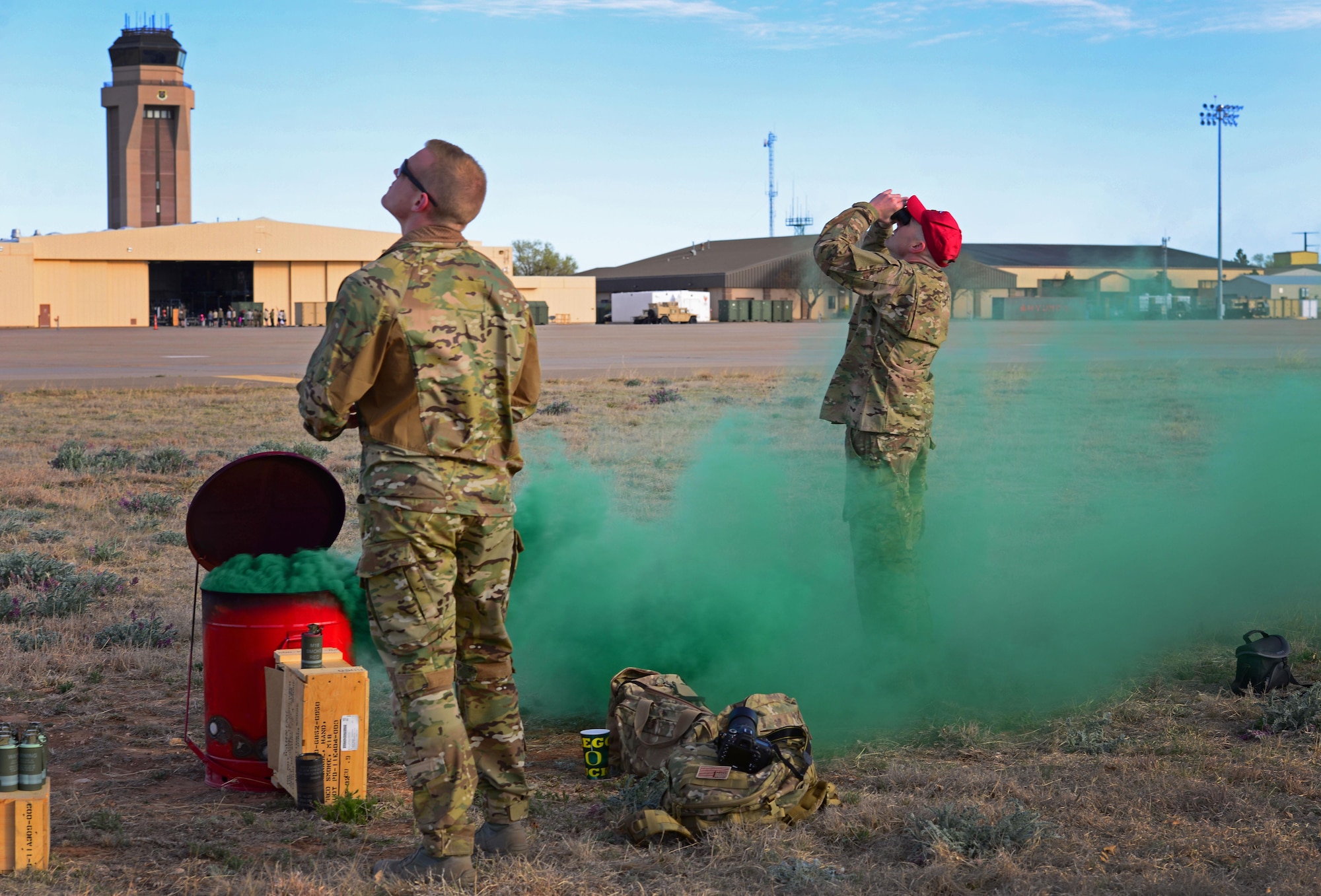 Members of the 26th Special Tactics Squadron watch as teammates parachute down from an aircraft overhead March 25, 2016, at Cannon Air Force Base, N.M. Dozens of 26th STS members performed routine practice jumps over the Cannon flightline, and relied on ground crews to use signals to help them safely touch-down at the designated landing zone. (U.S. Air Force photo/Staff Sgt. Alexx Pons) 