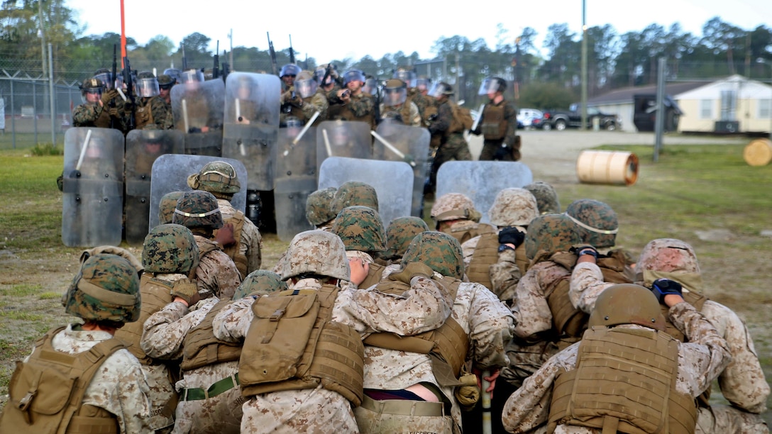 An opposing force kneels in front of a riot control squad with Combat Logistics Battalion 2 during the unit’s non-lethal weapons training final exercise at Marine Corps Base Camp Lejeune, North Carolina, March 25, 2016. The battalion had to qualify through the Expeditionary Operations Training Group, in preparation for their upcoming deployment with Special Purpose Marine Air-Ground Task Force-Crisis Response-Africa.