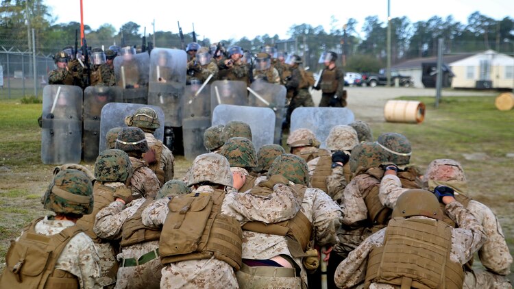 An opposing force kneels in front of a riot control squad with Combat Logistics Battalion 2 during the unit’s non-lethal weapons training final exercise at Marine Corps Base Camp Lejeune, North Carolina, March 25, 2016. The battalion had to qualify through the Expeditionary Operations Training Group, in preparation for their upcoming deployment with Special Purpose Marine Air-Ground Task Force-Crisis Response-Africa.