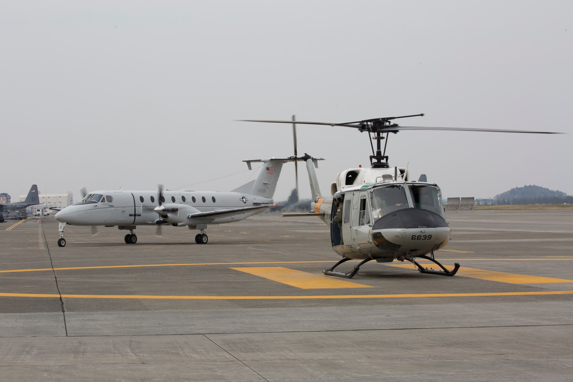 A UH-1 Iroquois and a C-12 Huron, both assigned to the 459th Airlift Squadron, prepare to take off during a training mission at Yokota Air Base, Japan, March 30, 2016. SECOND SENTENCE? (U.S. Air Force photo by Yasuo Osakabe/Released)