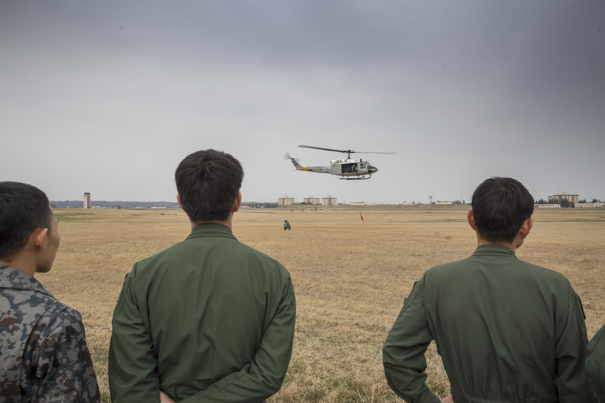Japan Air Self-Defense Force members from the 402nd Squadron watch a hoist demonstration performed by U.S. Air Force from the 459th Airlift Squadron at Yokota Air Base, Japan, March 30, 2016. Members with the 459th AS introduced their airlift capabilities, which were the Aeromedical Evacuation operation with a C-12 Huron and search and rescue capabilities with a UH-1 Iroquois. (U.S. Air Force photo by Yasuo Osakabe/Released)