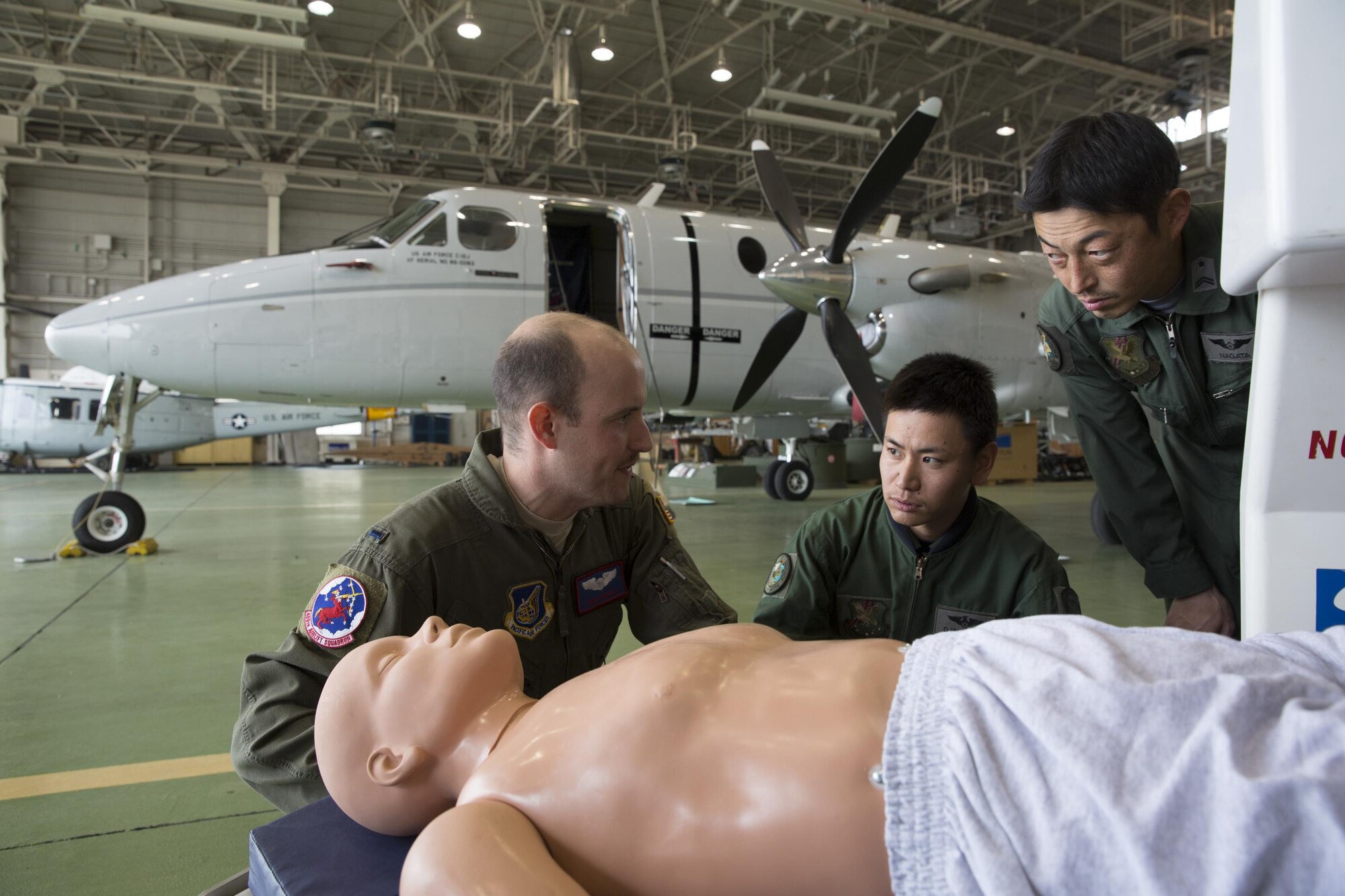 (Left to right) U.S. Air Force 1st Lt. Anthony Pergola, 459th Airlift Squadron C-12 pilot, talks about an Aeromedical Evacuation Spectrum Bed to Japan Air Self-Defense Capt. Daiki Ishihara, 402nd Squadron C-1 pilot, and JASDF Tech. Sgt. Shoji Nagata, 402nd Squadron C-1, U-4 loadmaster, at Yokota Air Base, Japan, March 30, 2016. Members with the 459th AS demonstrated Aeromedical Evacuation procedures of a C-12 Huron to JASDF members to improve the working relationship between JASDF and USAF. (U.S. Air Force photo by Yasuo Osakabe/Released)