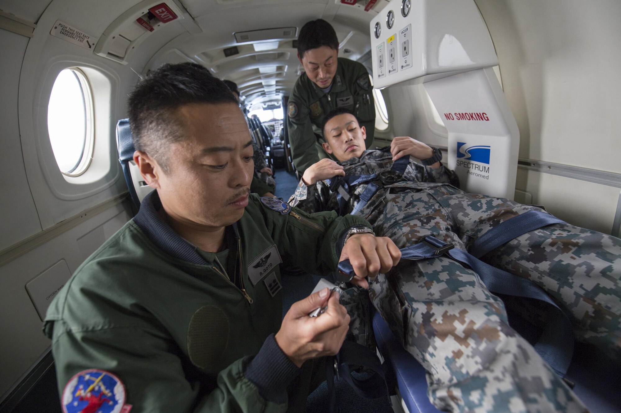 Japan Air Self-Defense Force Lt. Col. Ryoichi Goto, 402nd Squadron commander, secures a buckle of an Aeromedical Evacuation Spectrum Bed during an AE familiarization flight over Yokota Air Base, Japan, March 30, 2016. The 459th AS hosted an AE familiarization flight with a C-12 Huron for the 402nd SQ from Iruma Air Base, Japan. (U.S. Air Force photo by Yasuo Osakabe/Released)