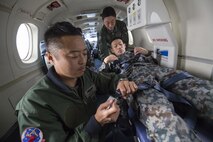 Japan Air Self-Defense Force Lt. Col. Ryoichi Goto, 402nd Squadron commander, secures a buckle of an Aeromedical Evacuation Spectrum Bed during an AE familiarization flight over Yokota Air Base, Japan, March 30, 2016. The 459th AS hosted an AE familiarization flight with a C-12 Huron for the 402nd SQ from Iruma Air Base, Japan. (U.S. Air Force photo by Yasuo Osakabe/Released)