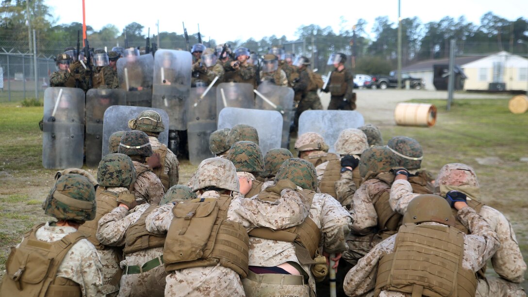 An opposing force kneels in front of a riot control squad with Combat Logistics Battalion 2 during the unit’s non-lethal weapons training final exercise at Camp Lejeune, N.C., March 25, 2016. The battalion had to qualify through the Expeditionary Operations Training Group, in preparation for their upcoming deployment with Special Purpose Marine Air-Ground Task Force-Crisis Response-Africa. (U.S. Marine Corps photo by Cpl. Joey Mendez)