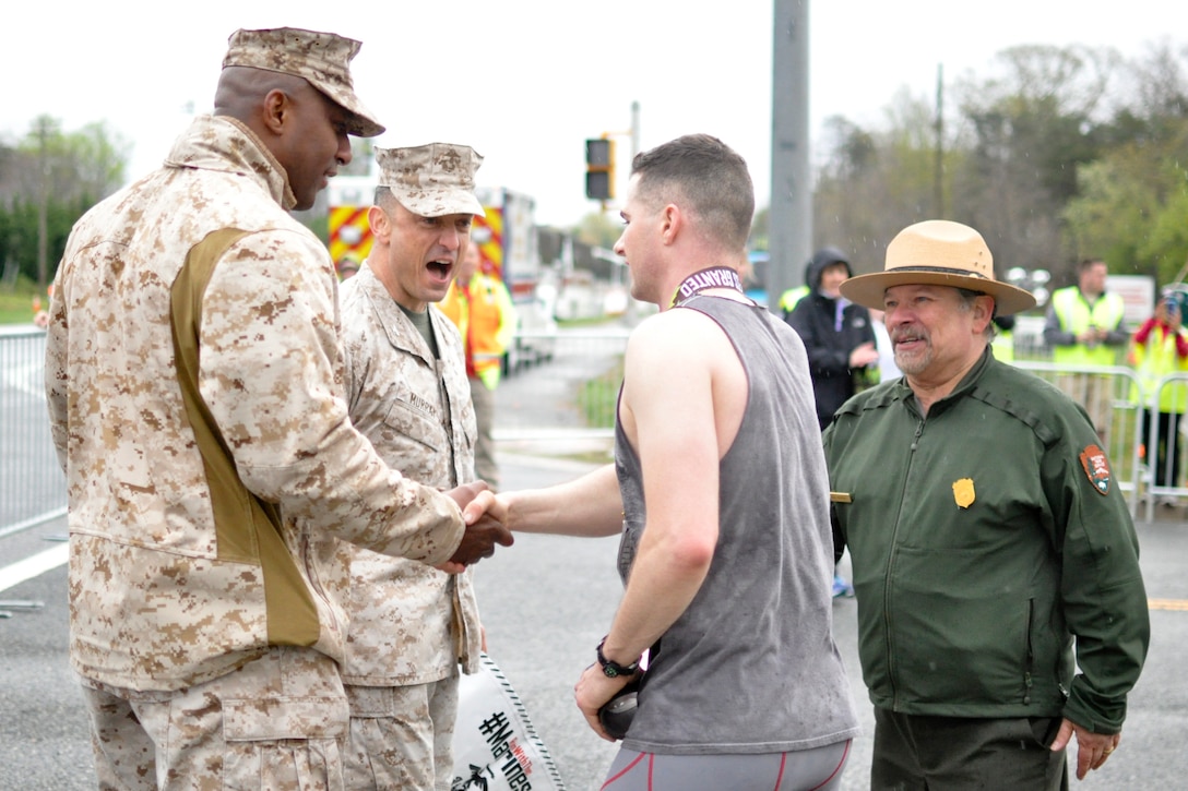 Col. Joseph Murray, base commander, Sgt. Maj. Gerald Saunders, base sergeant major, and Vidal Martinez, Prince William Forest Park superintendent, congratulate the first place finisher 2nd Lt. Andrew Harper, a student at The Basic School, during the Marine Corps Marathon 17.75K run through Prince William Forest Park on April 2.