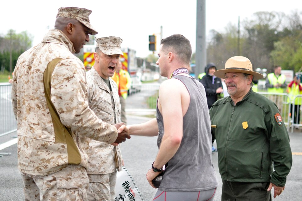 Col. Joseph Murray, base commander, Sgt. Maj. Gerald Saunders, base sergeant major, and Vidal Martinez, Prince William Forest Park superintendent, congratulate the first place finisher 2nd Lt. Andrew Harper, a student at The Basic School, during the Marine Corps Marathon 17.75K run through Prince William Forest Park on April 2.