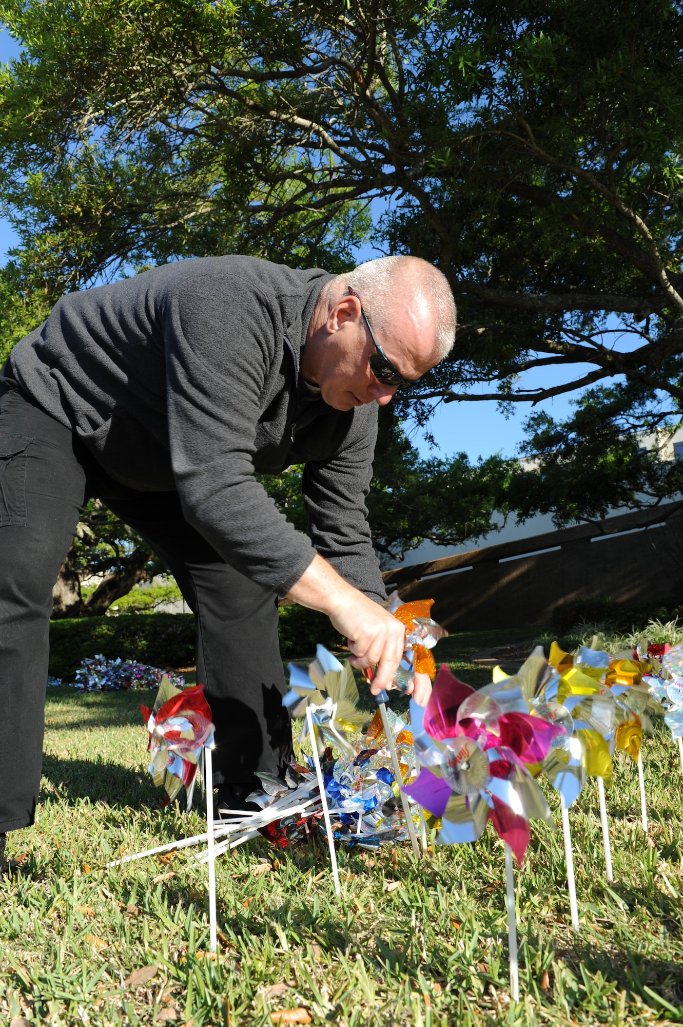 Gene Bumbalough, 81st Medical Operations Squadron alcohol drug abuse prevention and treatment medical support assistant, places pinwheels into the ground in front of the Keesler Medical Center April 4, 2016, Keesler Air Force Base, Miss. Family advocacy members and volunteers placed pinwheels to individually represent children in Harrison and Hancock counties who were victims of child abuse or neglect last year. (U.S. Air Force photo by Kemberly Groue)