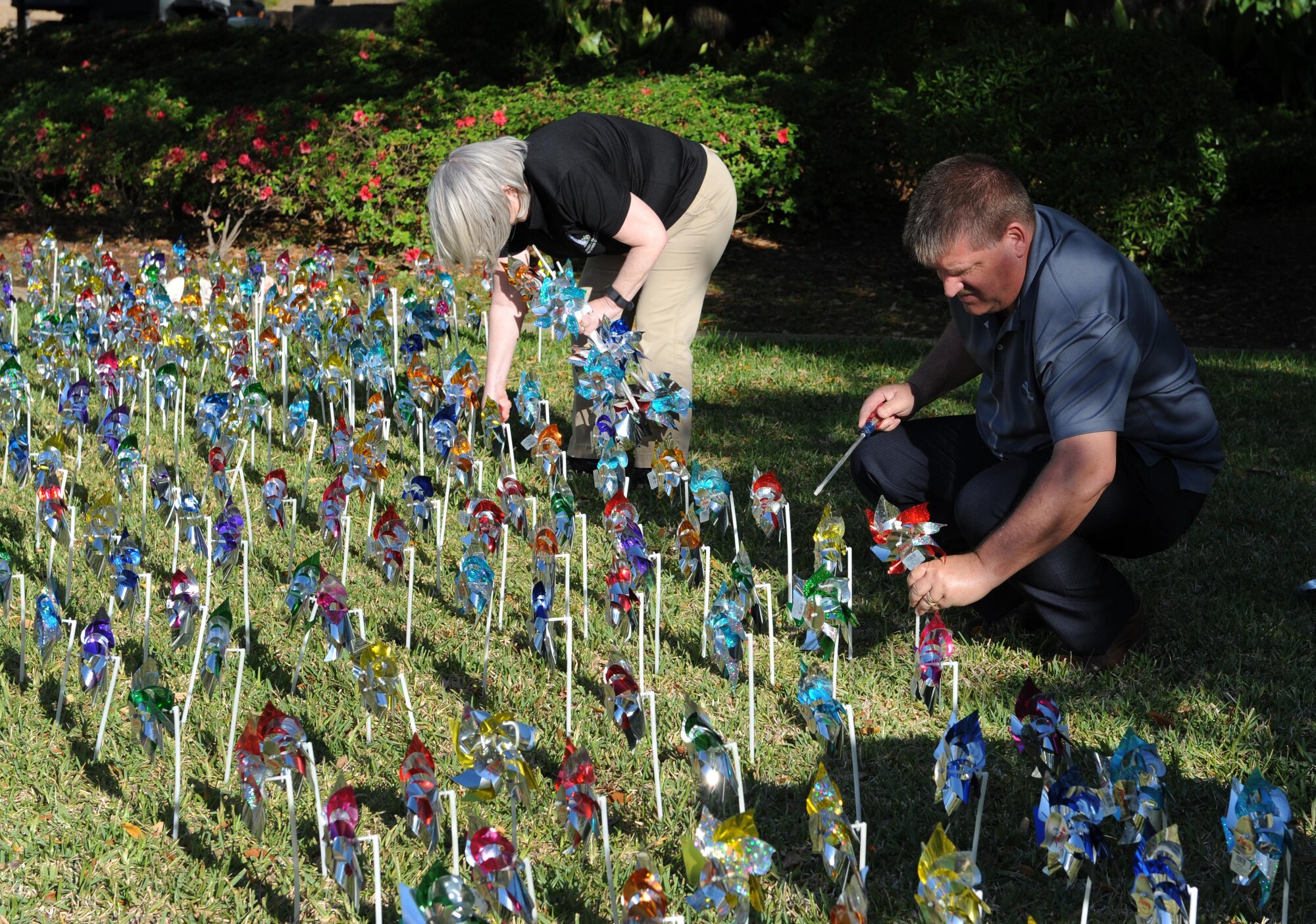 Jackie Pope, 81st Force Support Squadron airman and family readiness center chief, and John Lowe, 81st FSS community readiness consultant, place pinwheels into the ground in front of the Keesler Medical Center April 4, 2016, Keesler Air Force Base, Miss. Members of the 81st Medical Operations Squadron family advocacy and volunteers placed pinwheels to individually represent children in Harrison and Hancock counties who were victims of child abuse or neglect last year. (U.S. Air Force photo by Kemberly Groue)
