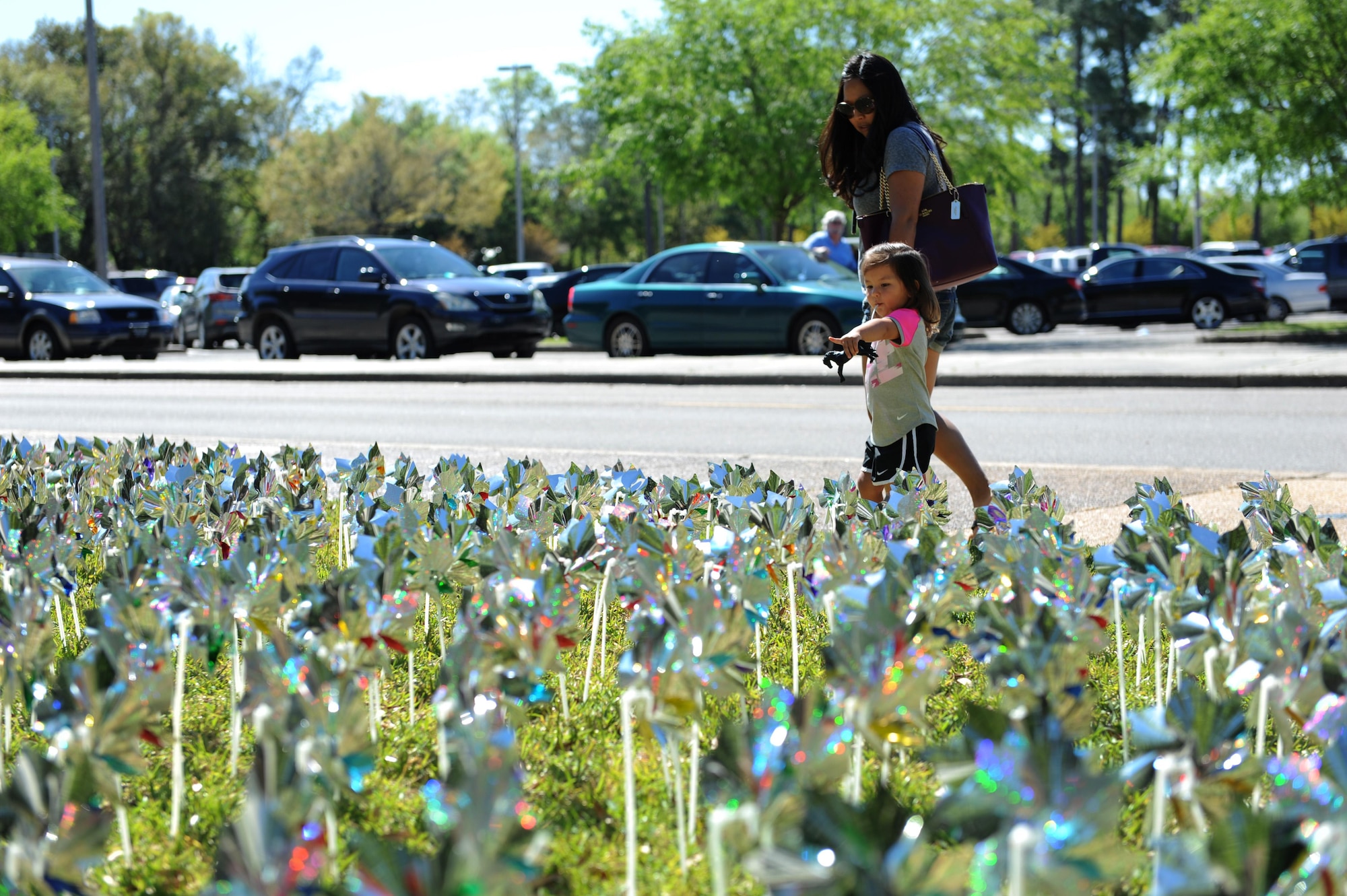 Cara and Mia, family of Tech. Sgt. Blaine Caudill, 81st Operations Support Flight air traffic control watch supervisor, admires the group of pinwheels placed into the ground in front of the Keesler Medical Center April 4, 2016, Keesler Air Force Base, Miss. Members of the 81st Medical Operations Squadron family advocacy and volunteers placed pinwheels to individually represent children in Harrison and Hancock counties who were victims of child abuse or neglect last year. (U.S. Air Force photo by Kemberly Groue)