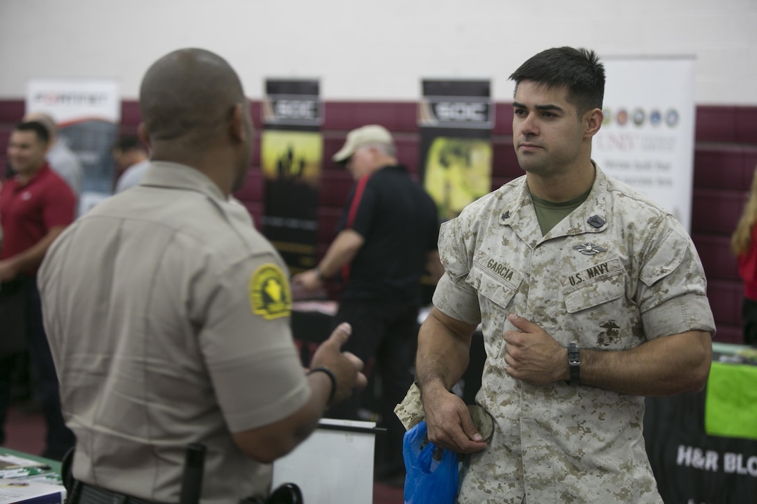 Petty Office 3rd Class, Adrian Garcia, corpsman, Marine Wing Support Squadron 374, asks Officer Kris Powers, recruiter, San Bernardino County Sherrif’s Department, a question about his agency at the Education and Career Fair at the West Gym, March 23, 2016.( Official Marine Corps photo by Cpl. Julio McGraw/Released)