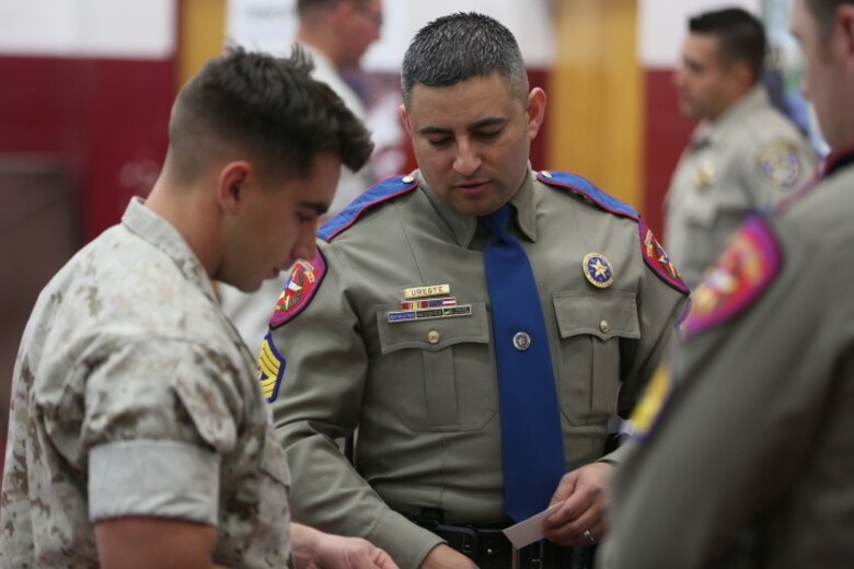 Sergeant Octavio Ureste, recruiter, Texas Department of Public Safety, talks to Cpl. Will Parker, refrigeration and air conditioning mechanic, Marine Wing Support Squadron 374, about his agency during the Education and Career Fair at the West Gym, March 23, 2016.( Official Marine Corps photo by Cpl. Julio McGraw/Released)