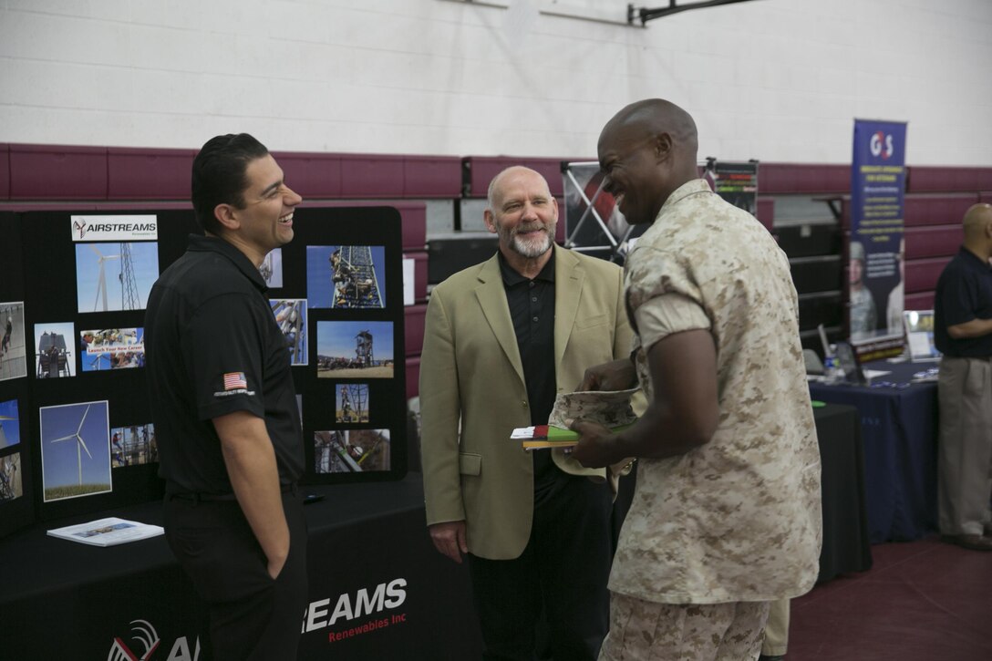 Frank E. Pulley and Adrian Cervantes, regional admissions representatives, Airstreams Renewables, talk to Sgt. Adrian Johnson, motor vehicle operator, Marine Wing Support Squadron 374, about their company during the Education and Career Fair at the West Gym, March 23, 2016.( Official Marine Corps photo by Cpl. Julio McGraw/Released)