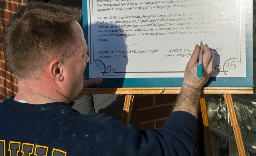 Capt. Scott Fuller, Naval Air Facility Washington commanding officer, signs a proclamation after the second annual Consent to Color 5k run here, April 4, 2016. the event signified the recognition of April as Sexual Assault Awareness Month. (U.S. Air Force photo by Senior Airman Ryan J. Sonnier/RELEASED)