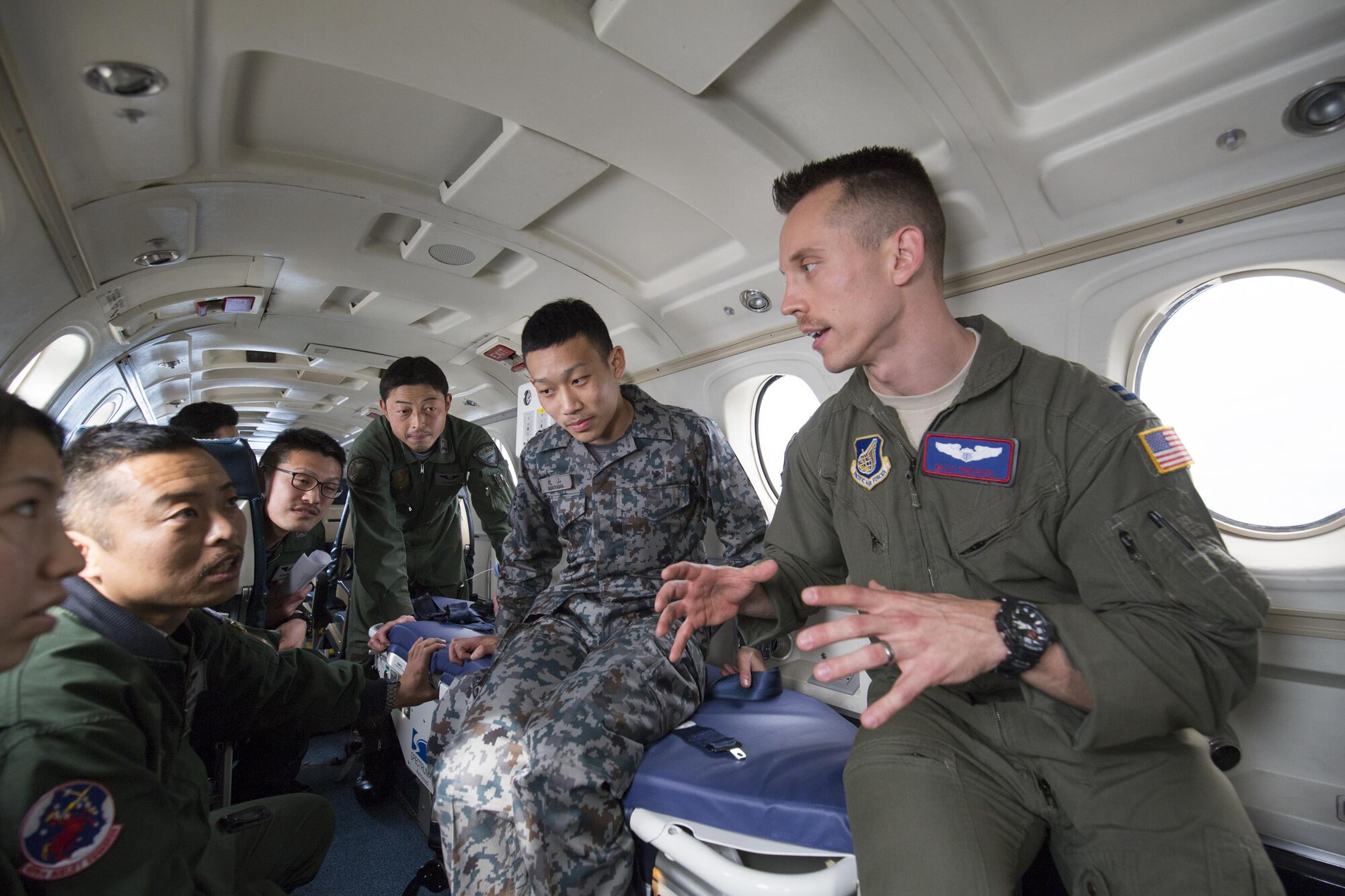 U.S. Air Force Capt William Poeschl, 459th Airlift Squadron C-12 pilot, briefs Japan Air Self-Defense Force members of the 402nd Squadron during an Aeromedical Evacuation familiarization flight over Yokota Air Base, Japan, March 30, 2016. 459 AS members demonstrated Aeromedical Evacuation operations of a C-12 Huron to JASDF members to improvement the working relationship between JASDF and USAF. (U.S. Air Force photo by Yasuo Osakabe/Released)