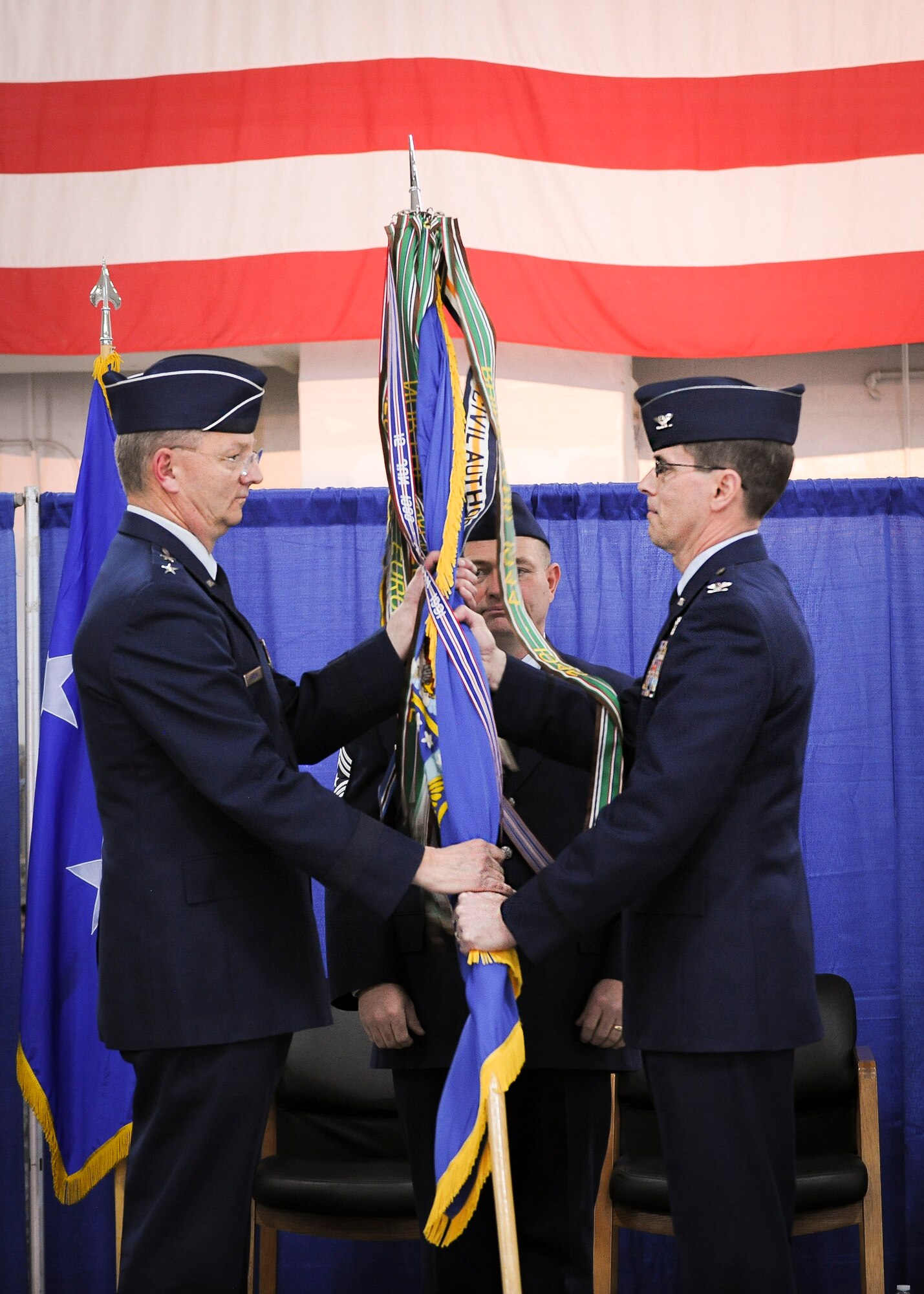 Col. Greg Semmel, 174th Attack Wing commander, hands the wing's colors over to Maj. Gen. Anthony German, the commander of the New York Air National Guard, signifying the transfer of the command, during a ceremony held at Hancock Field Air National Guard Base, April 3. (U.S. Air National Guard photo by Tech. Sgt. Jeremy Call/Released)