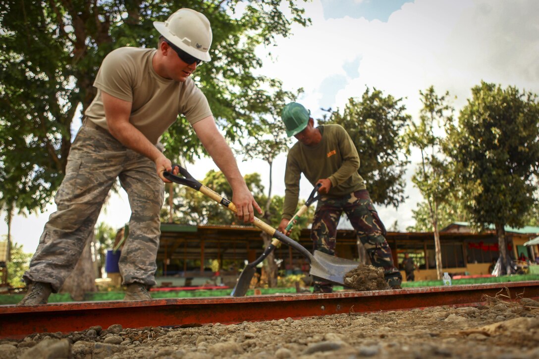 Air Force Staff Sgt. Kyle Gould, left, and Philippine Army Cpl. Gilbert Balobalo level dirt for a basketball court during Exercise Balikatan 2016 at Jaena Norte Elementary School in Capiz, Philippines, April 2, 2016. Gould is assigned to the 673rd Expeditionary Engineer Squadron and Balobalo is assigned to 552 Engineer Construction Battalion. Marine Corps photo by Cpl. Hilda M. Becerra
