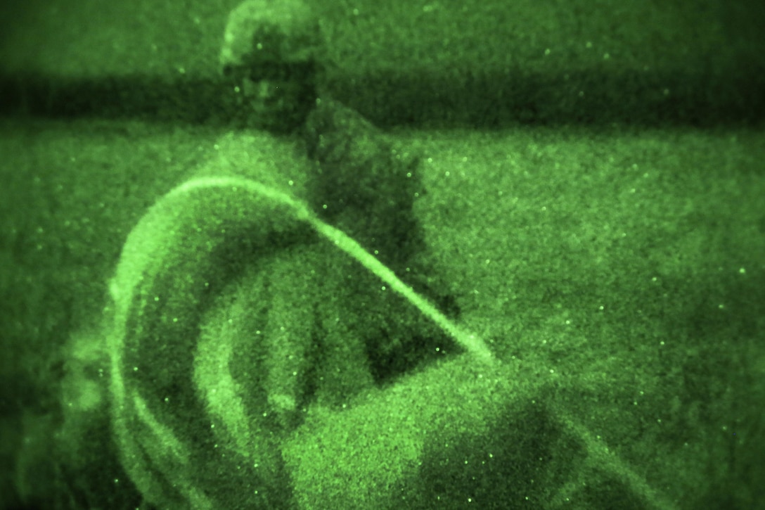As seen through a night-vision device, a paratrooper recovers his chute after participating in a night airborne operation onto Malemute drop zone at Joint Base Elmendorf-Richardson, Alaska, March 31, 2016. Air Force photo by Alejandro Pena