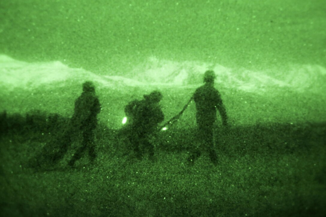 As seen through a night-vision device, paratroopers proceed to the rally point after participating in a night airborne operation onto Malemute drop zone at Joint Base Elmendorf-Richardson, Alaska, March 31, 2016. Air Force photo by Alejandro Pena