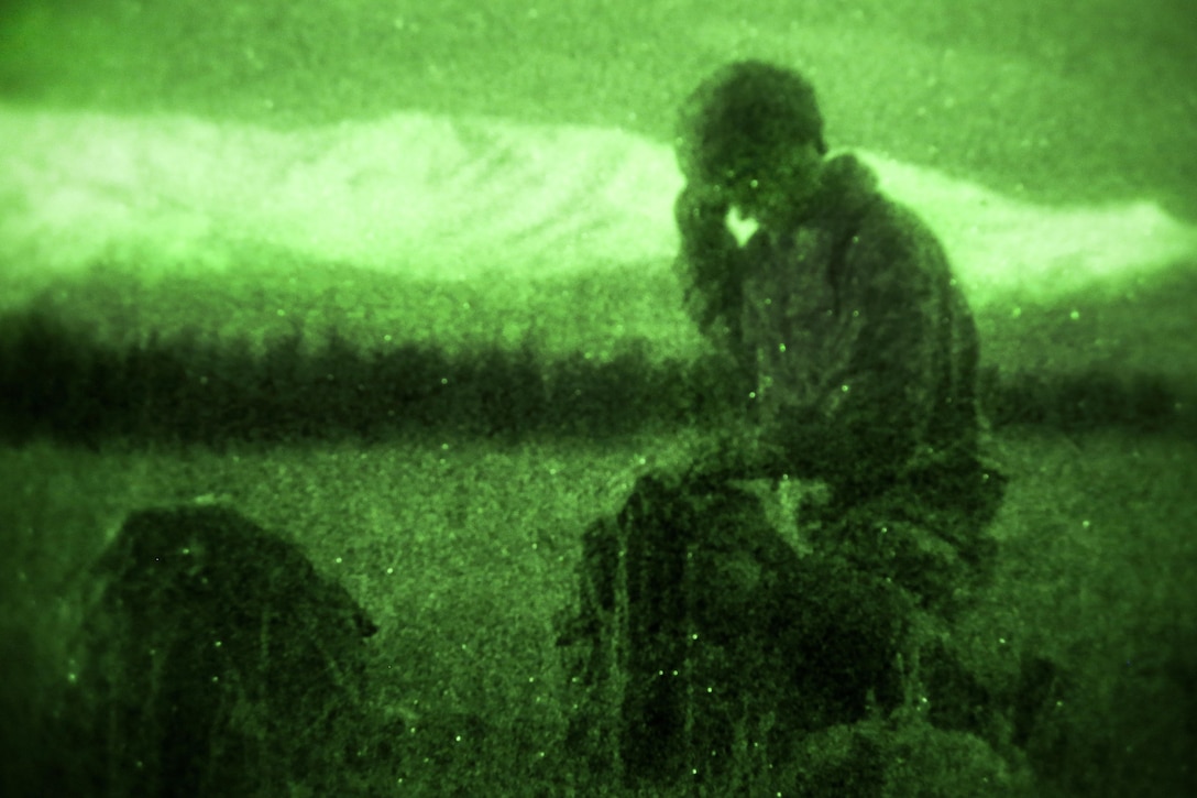 As seen through a night-vision device, a paratrooper recovers his chute and gear after participating in a night airborne operation onto Malemute drop zone at Joint Base Elmendorf-Richardson, Alaska, March 31, 2016. Air Force photo by Alejandro Pena