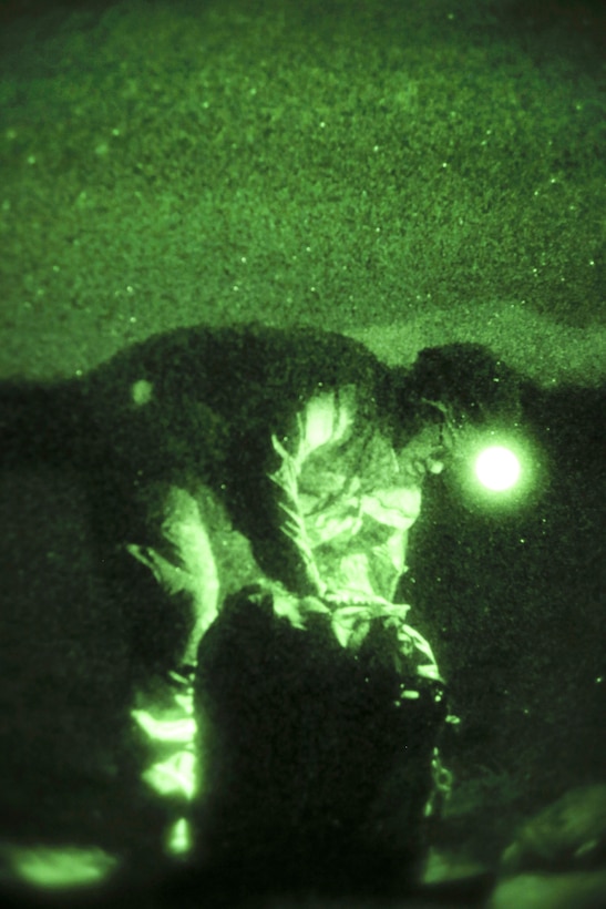 As seen through a night-vision device, a paratrooper recovers his chute after participating in a night airborne operation onto Malemute drop zone at Joint Base Elmendorf-Richardson, Alaska, March 31, 2016. Air Force photo by Alejandro Pena