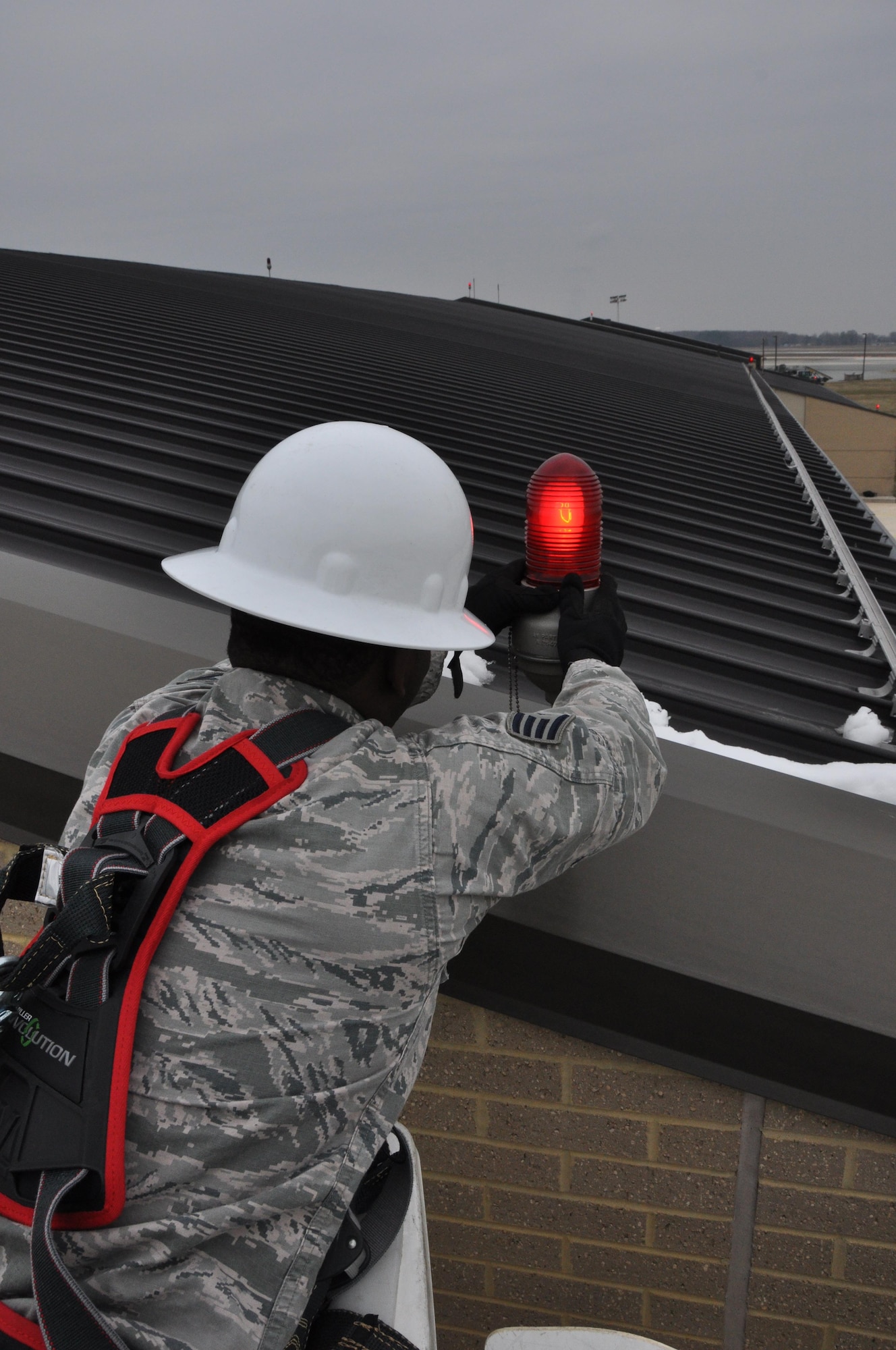 Staff Sgt. Terrill Strothers, 512th Civil Engineer Squadron electrical technician, resets the housing for the 100-watt signal light located on the roof of the base firehouse March 6, 2016 at Dover Air Force Base, Delaware. The roof lights make the firehouse easy to identify by approaching aircraft in case of emergencies. (U.S. Air Force photo/Staff Sgt. Joe Yanik)