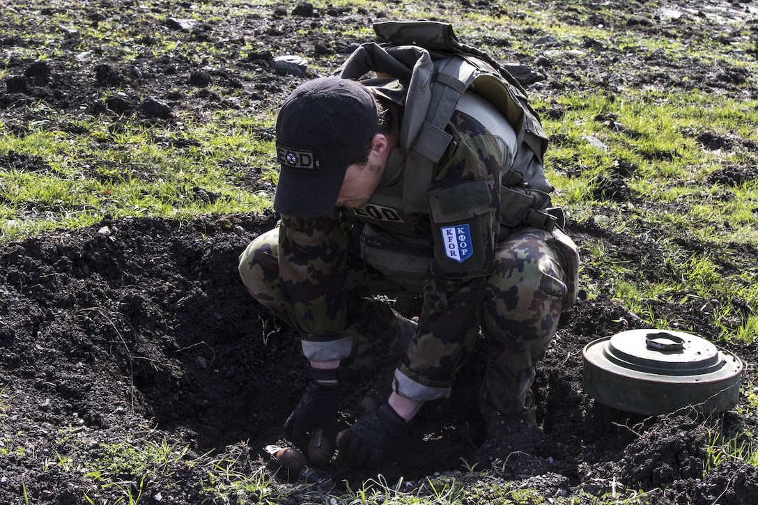 A Swiss soldier places an unexploded ordnance into an individual pot during a joint mine clearing operation at Orahovac Demolition Range in Kosovo, April 4, 2016. Army photo by Staff Sgt. Thomas Duval