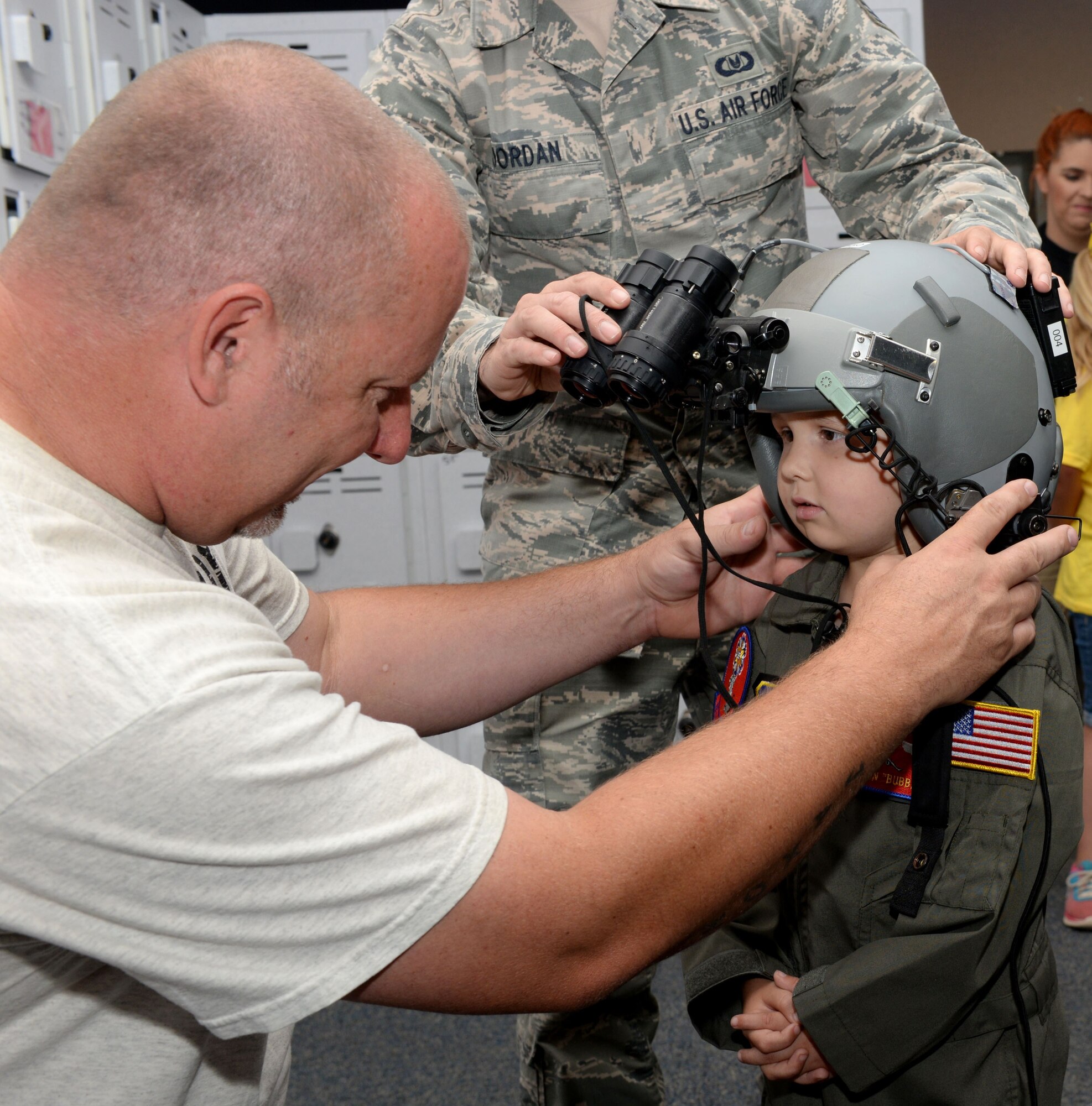 ALTUS AIR FORCE BASE, Okla. – Cody Dugger helps his son, Jaxon, put on a flight helmet equipped with nightvision goggles at the 97th Operations Support Squadron, June 26, 2015. Jaxon was diagnosed with Ewing’s sarcoma when he was two years old. (U.S. Air Force photo by Airman 1st Class Kirby Turbak/Released)