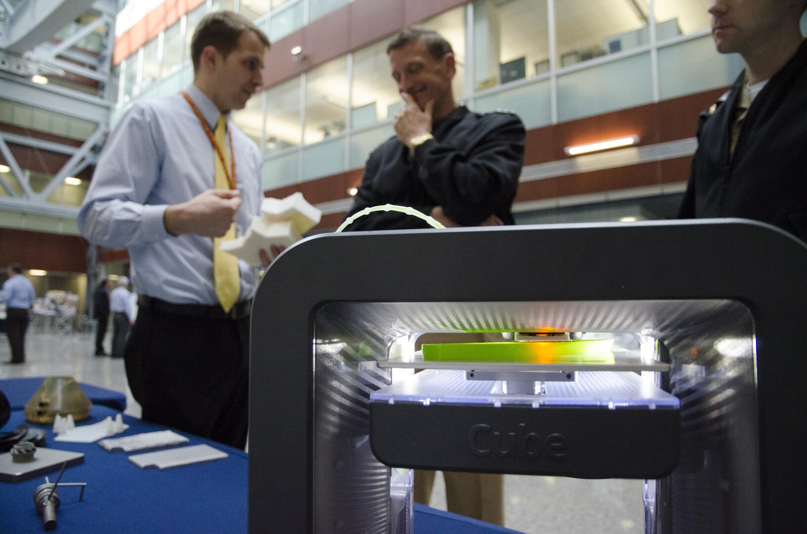 Ben Bouffard, an engineer representing additive manufacturing (AM) technology at Naval Surface Warfare Center, Carderock Division, talks to Vice Adm. William Hilarides, commander, Naval Sea Systems Command, during Carderock Day at the Washington Navy Yard, March 23,
2016. In the foreground a 3-D printer creates a model ship. (U.S. Navy photo by Monica McCoy/Released)