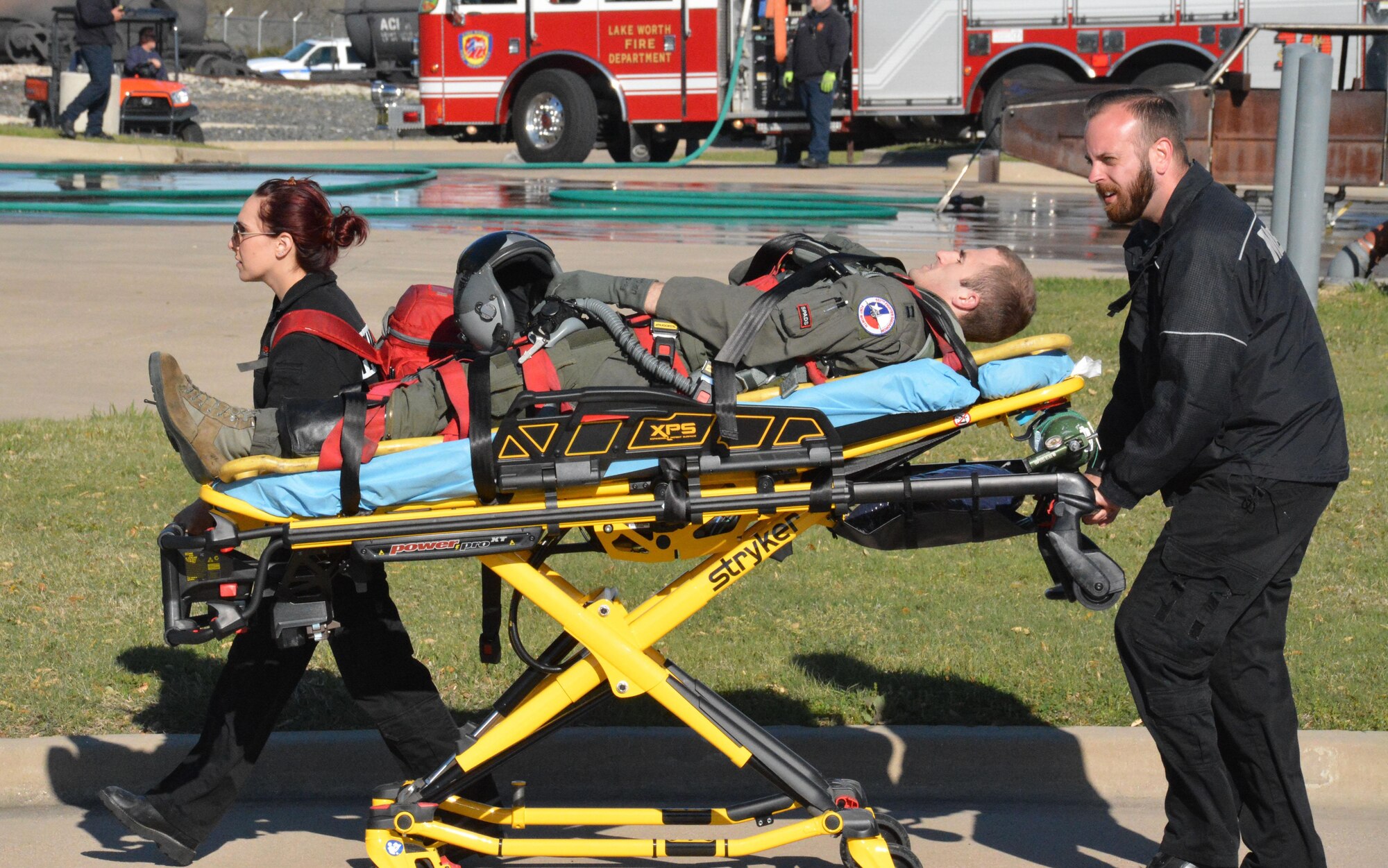Capt. John Patten, 457th Fighter Squadron F-16 pilot, rides on a stretcher March 22 with two MedStar Mobile Healthcare technicians guiding him, Tarrant County College, Fort Worth, Texas. Patten acted as one of the injured personnel MedStar treated during an exercise involving multiple emergency management agencies. (U.S. Air Force photo by Staff Sgt. Samantha Mathison)