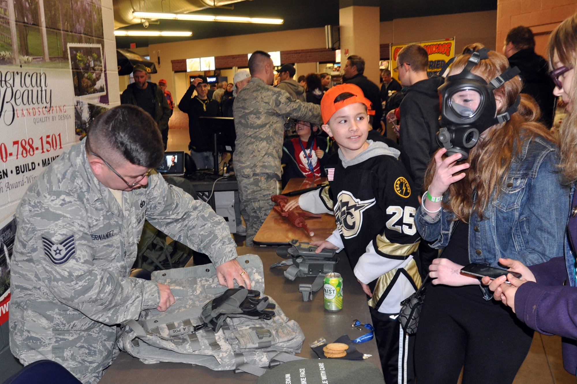 Tech. Sgt. Adam Hernandez, a fire team member assigned to 910th Security Forces Squadron, shows a body armor vest and a protective mask to hockey fans at a table display of unit equipment during pre-game festivities in the concourse of the Covelli Centre here, April 2, 2016. A group of Citizen Airmen, based at nearby Youngstown Air Reserve Station, Ohio, participated in YARS Night Out activities before and during the game. The Phantoms, a member of the United States Hockey League, defeated the Omaha Lancers 4-1 in front of a home ice crowd of more than 3000 fans. (U.S. Air Force photo/Master Sgt. Bob Barko Jr.)