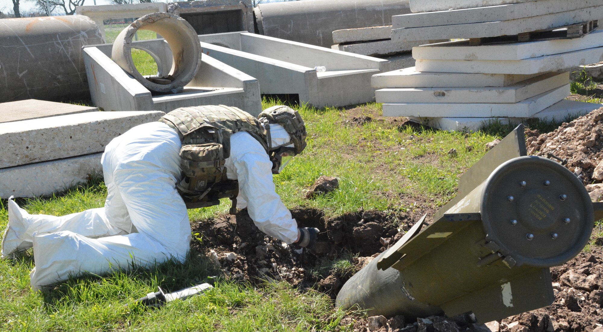 Staff Sgt. Chris Dolan, 301st Explosive Ordnance Disposal Flight technician, evaluates a training bomb in a crater March 22 at Tarrant County College, Fort Worth, Texas. 301st EOD Airmen practiced disarming procedures on two training bombs during an exercise involving an F-16 crash. (U.S. Air Force photo by Staff Sgt. Samantha Mathison)
