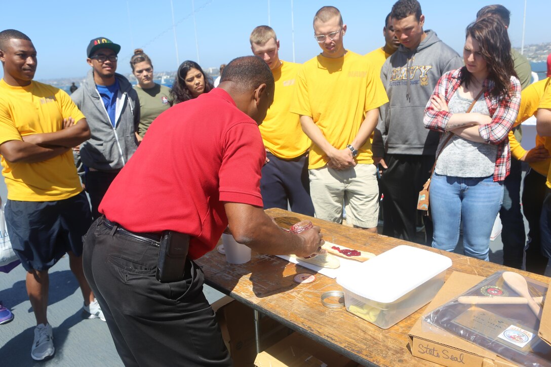 Marines with Marine Corps Air Station Miramar’s Single Marine Program and Sailors watch a demonstration during the Stem-to-Stern PB & J challenge aboard the USS Midway Museum in San Diego, Calif., April 2, 2016. The Marines competed with 20 local Sailors to make the world’s longest peanut butter and jelly sandwich made on a military vessel.