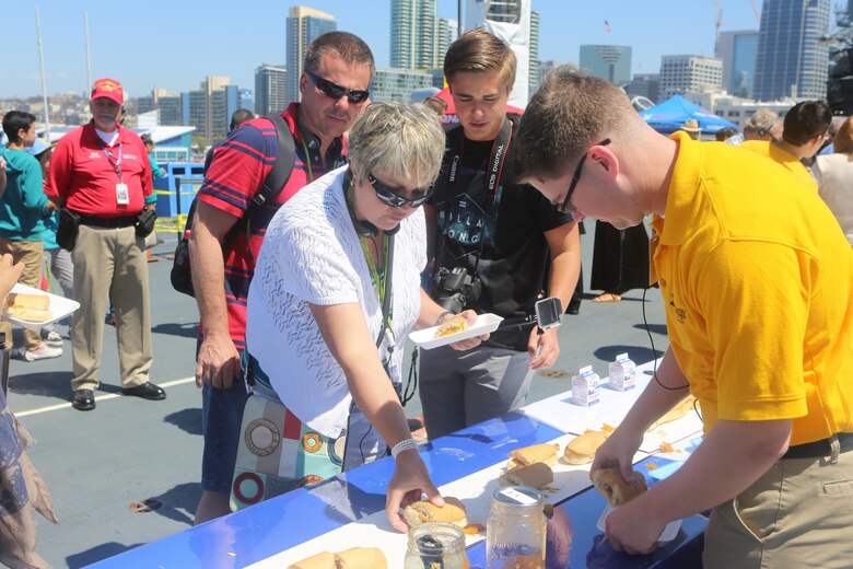 A member of the San Diego community grabs a piece of the peanut butter and jelly sandwich made during the Stem-to-Stern PB & J challenge aboard USS Midway Museum in  San Diego, Calif., April 2, 2016. Twenty Marines stationed at Marine Corps Air Station Miramar, Calif., competed with 20 local Sailors to build the world’s largest peanut butter and jelly sandwich made on a military vessel.