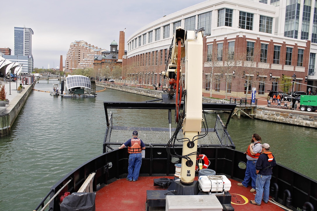 The crew on board the Reynolds, U.S. Army Corps of Engineers' steel debris vessel, approaches the Waterwheel Powered Trash Interceptor, also known as Mr. Trash Wheel, located in the Baltimore Inner Harbor on April 4, 2016. Col. Edward Chamberlayne, Commander, Baltimore District, visited with the team behind Mr. Trash Wheel to discuss similarities in their respective missions toward a cleaner Baltimore Harbor.